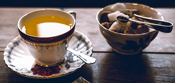 taza de té y taza de azúcar moreno sobre mesa de madera