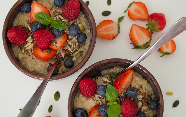comida en un bol compuesta de porridge con fresas y arandanos