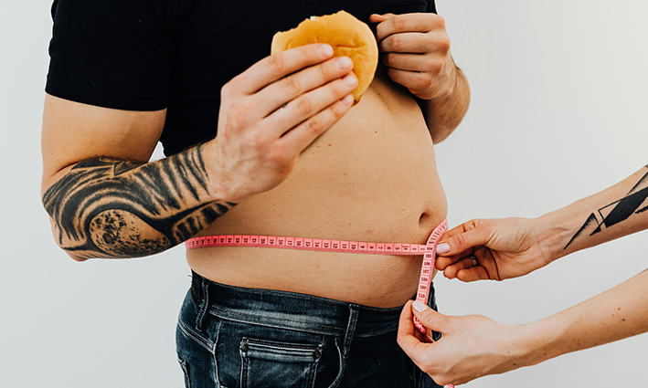 hombre con barriga gruesa con pan en la mano muestra indicio de carencia de vitamina D