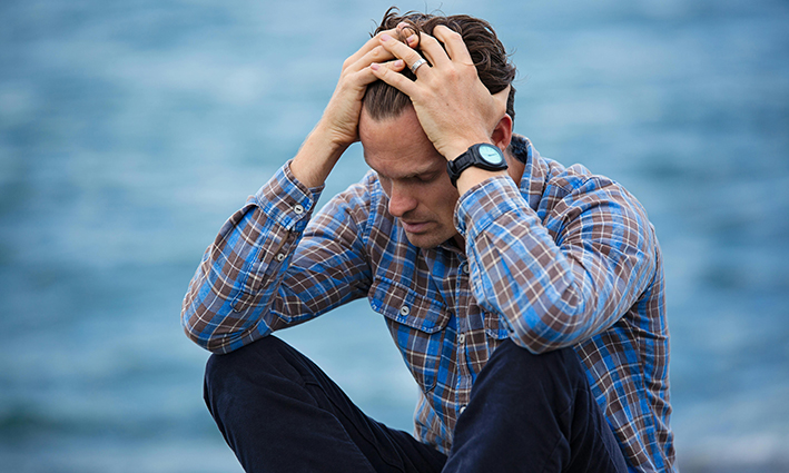 hombre con las manos apoyadas sobre la cabeza en un día nublado muestra la falta de vitamina D y la salud mental