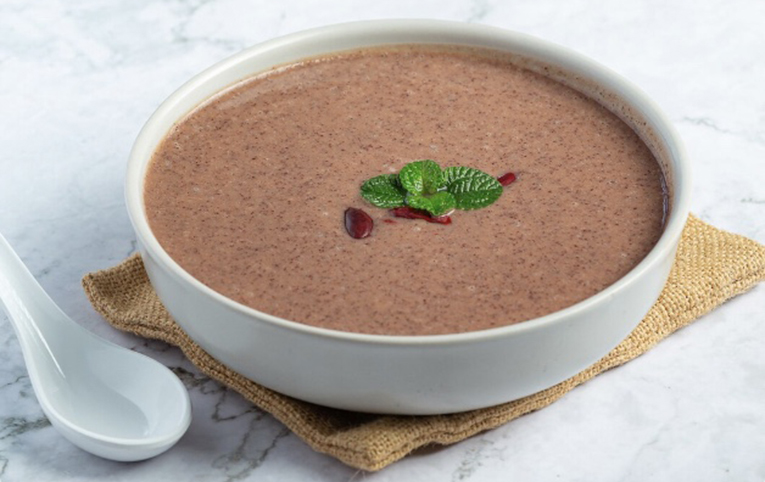 Receta con alubias y azukis coronada con hojas de menta, dentro de un bol y encima de una tela de arpillera