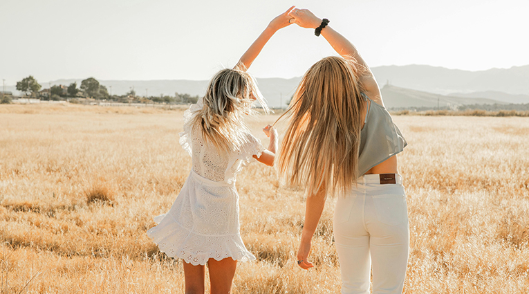 mujeres rubias de espaldas cogidas de las manos frente al sol equilibrando los ritmos circadianos